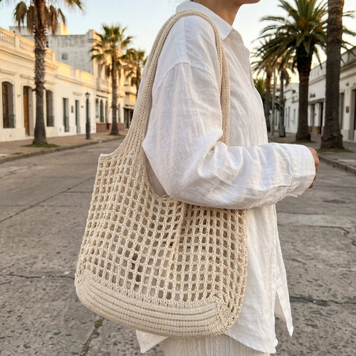 Mujer con camisa de lino llevando al hombro el bolso Médano tejido blanco